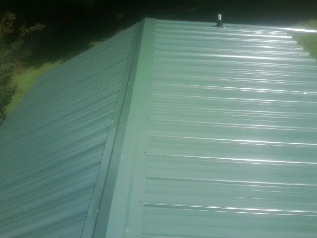 New green metal panels meeting at the ridge of a roof — Flat Roof Repair work by our crew in Walla Walla