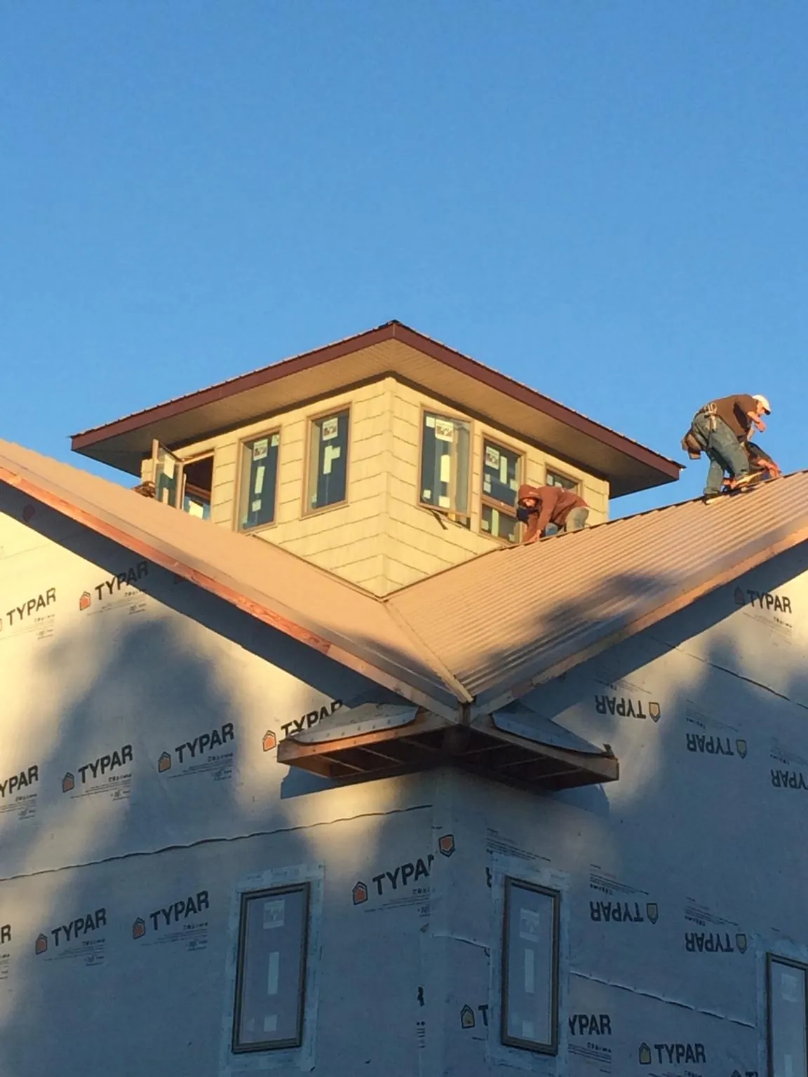 Roofers working around a rooftop cupola on a new metal roof at sunset — Roof Waterproofing in Walla Walla by Roofing Brothers